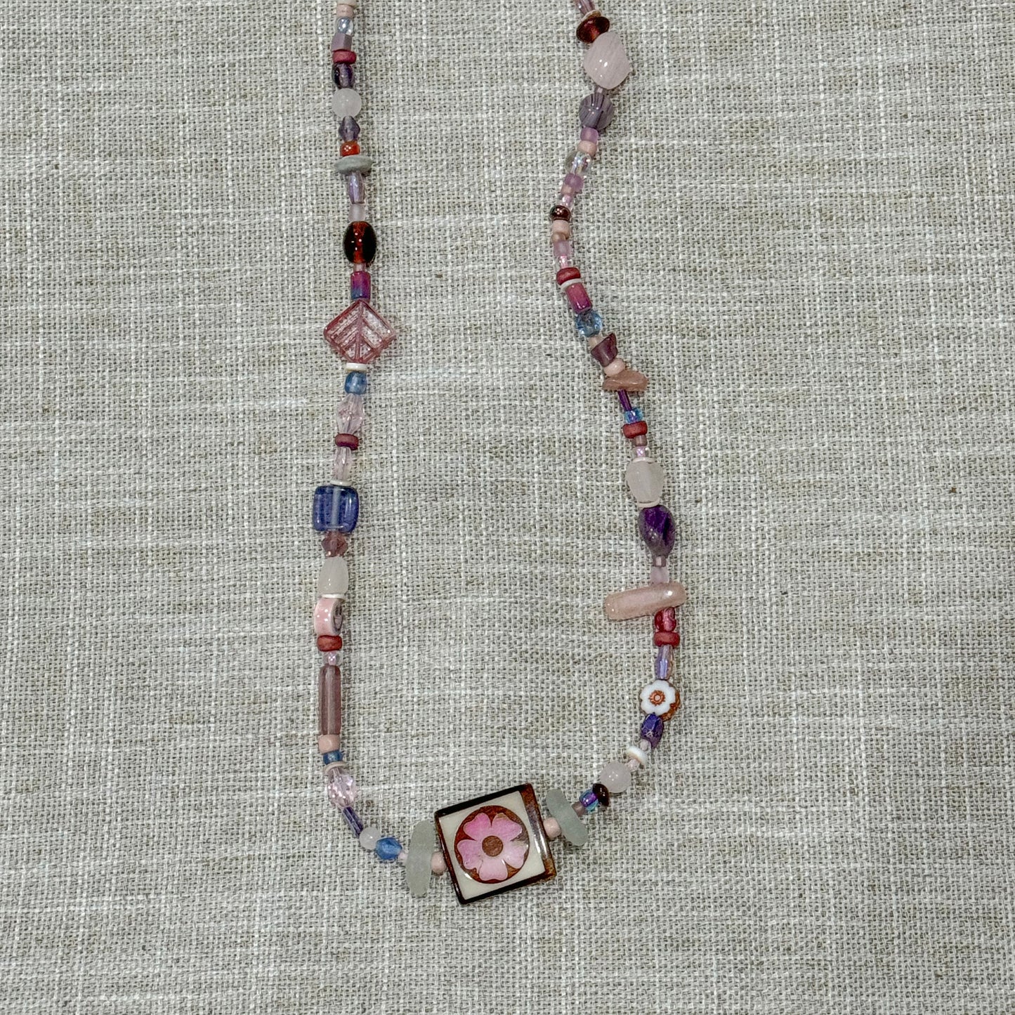 Handmade beaded necklaces with sea glass found on the shores of Lake Michigan. Features square statement flower bead