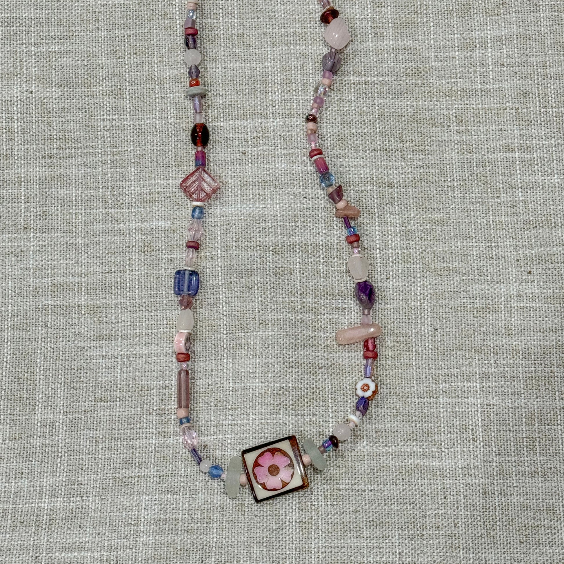 Handmade beaded necklaces with sea glass found on the shores of Lake Michigan. Features square statement flower bead