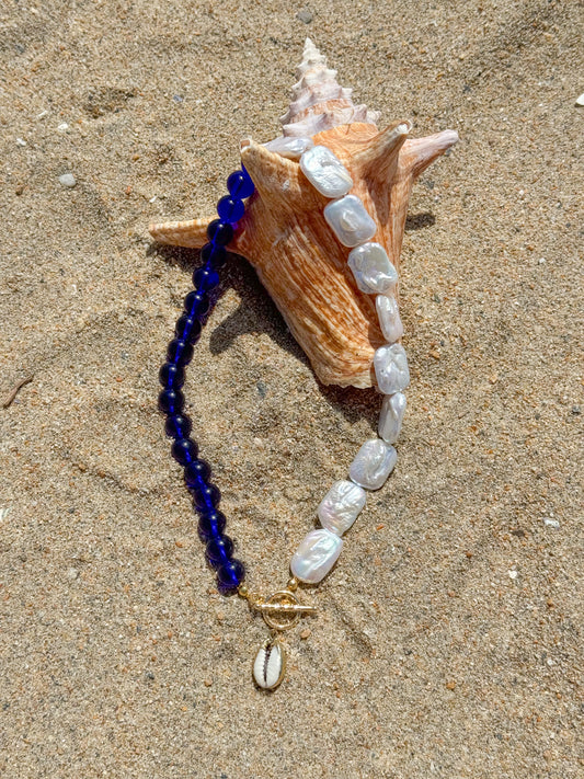 Necklace with blue and white beads on a sand background